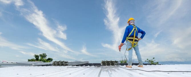 A Roofer using electric drill nail gun installing PU foam roof sheet at under construction. Safety body construction, Working at height equipment. building