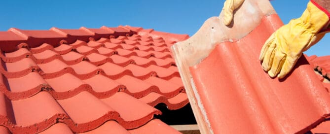 Roofer replacing red roof tiles