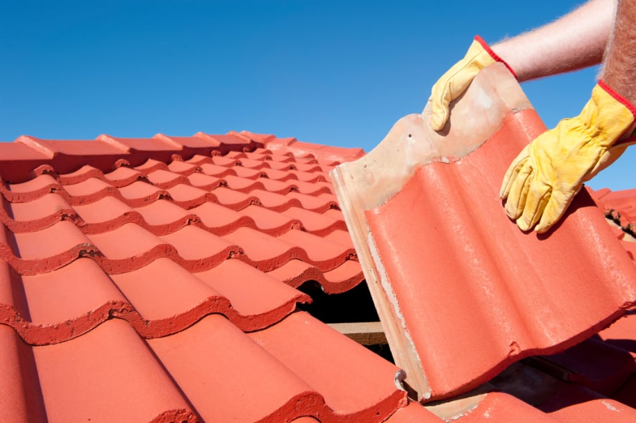 Roofer replacing red roof tiles