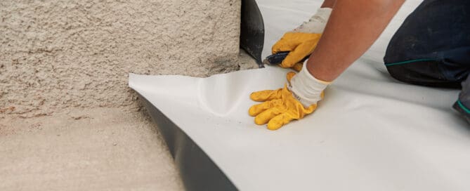 Worker with gloves in the process of installing TPO roofing.