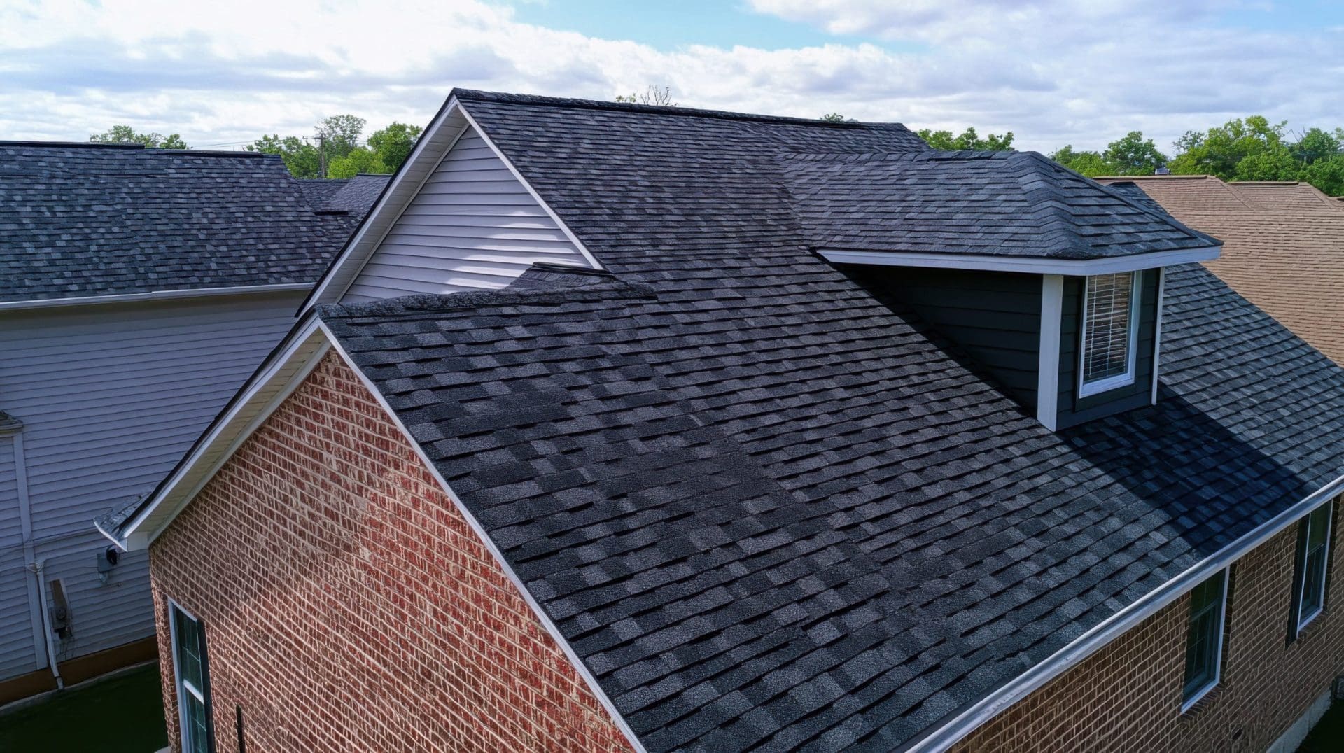 Roofer installing asphalt shingles on a suburban house. Featuring roof repair and weatherproofing.