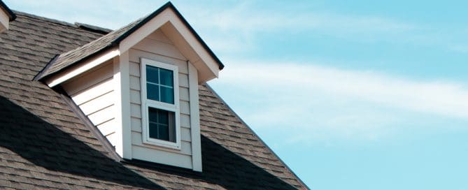 The close up image of authentic European house roof and roof window in blue sky with cloud.
