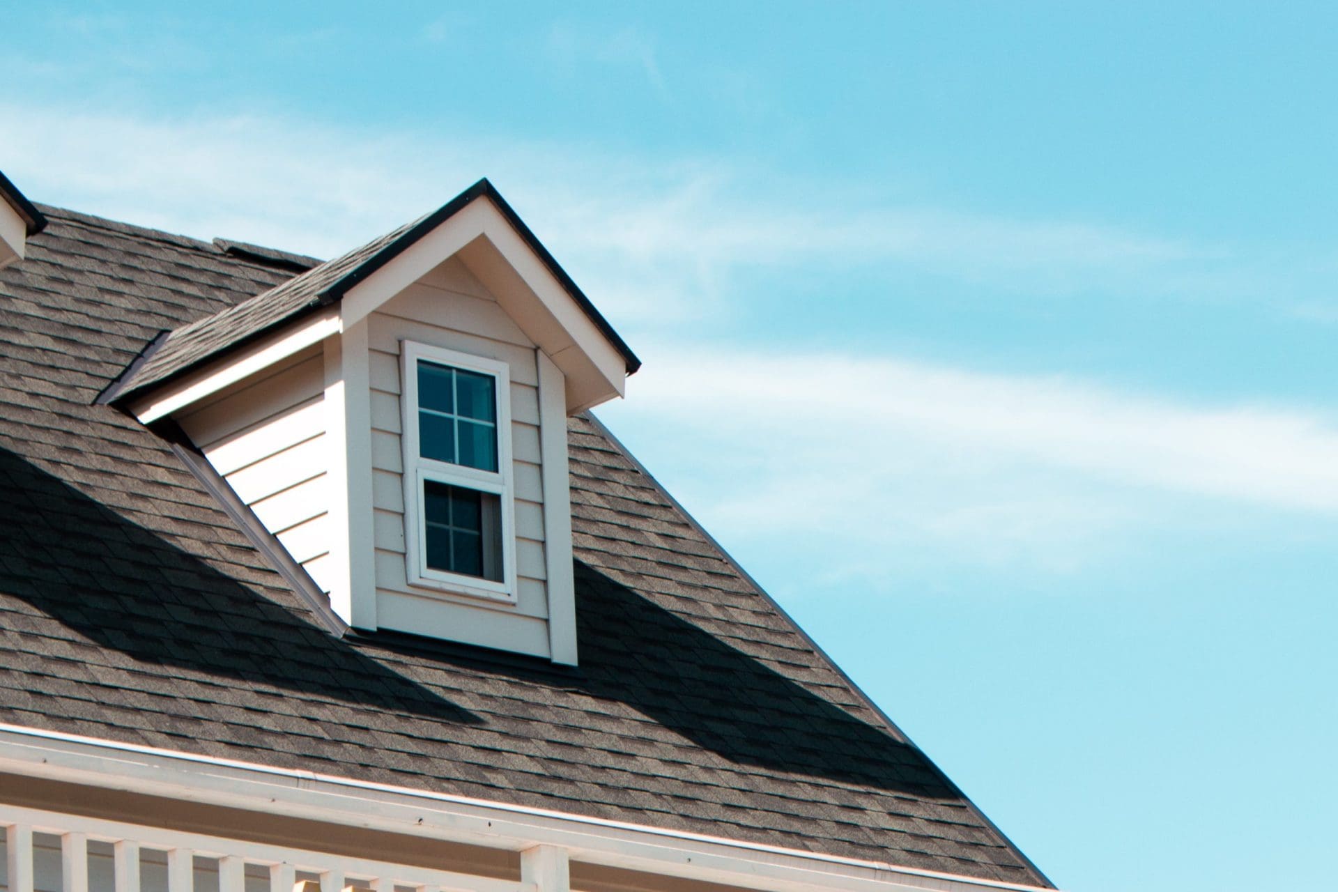 The close up image of authentic European house roof and roof window in blue sky with cloud.