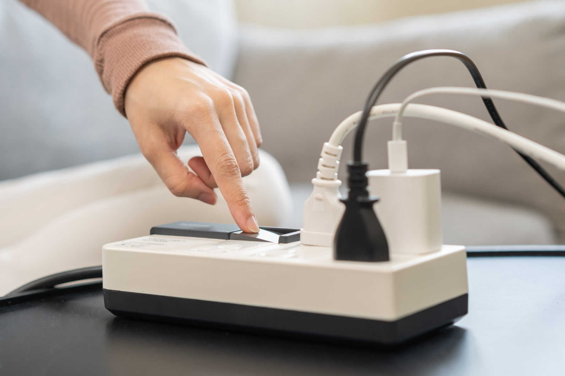 A person turning off a power strip full of plugged-in devices.