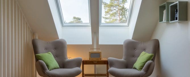 A cozy seating area with two armchairs under large skylight windows, letting in natural light and offering a view of the trees outside.