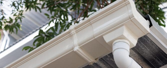 White plastic rain gutter of roof of house. vinyl rain gutter and downpipe.