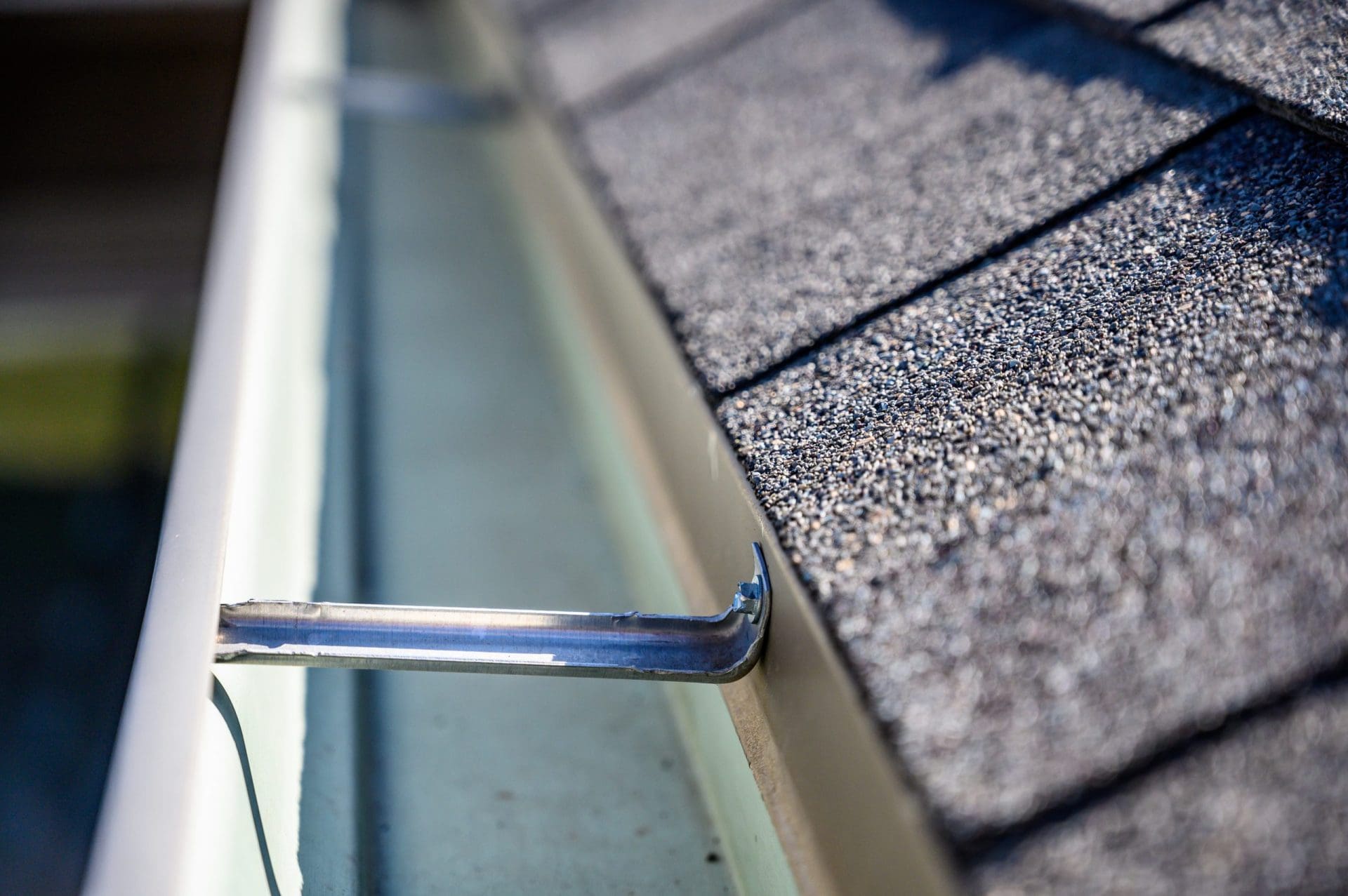 View inside roof gutter with clips and edge of shingles.