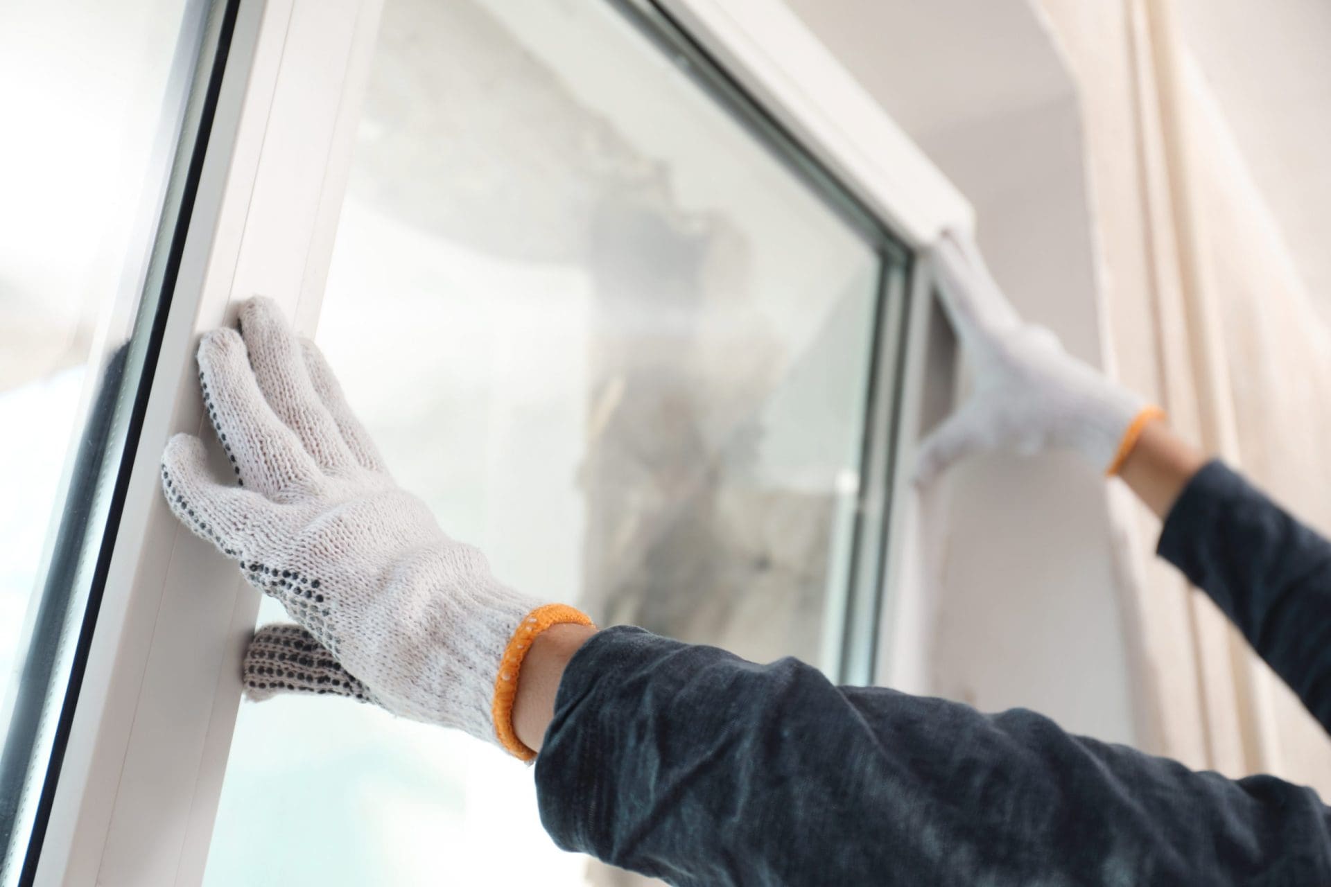 Worker installing plastic window indoors, closeup view.