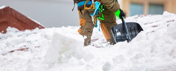 Person shoveling snow from roof.