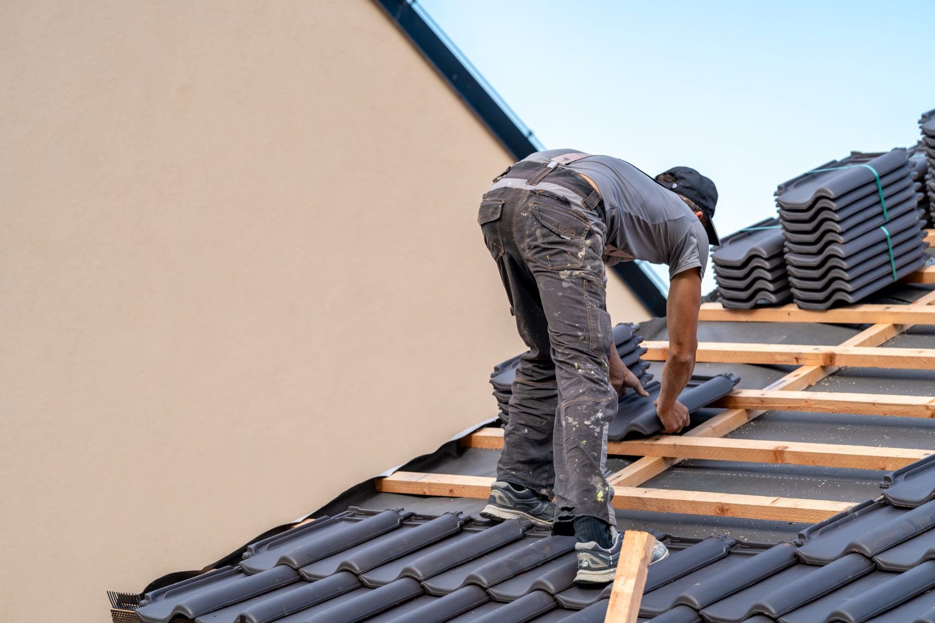 Roofer installs a fired ceramic tile on the roof.