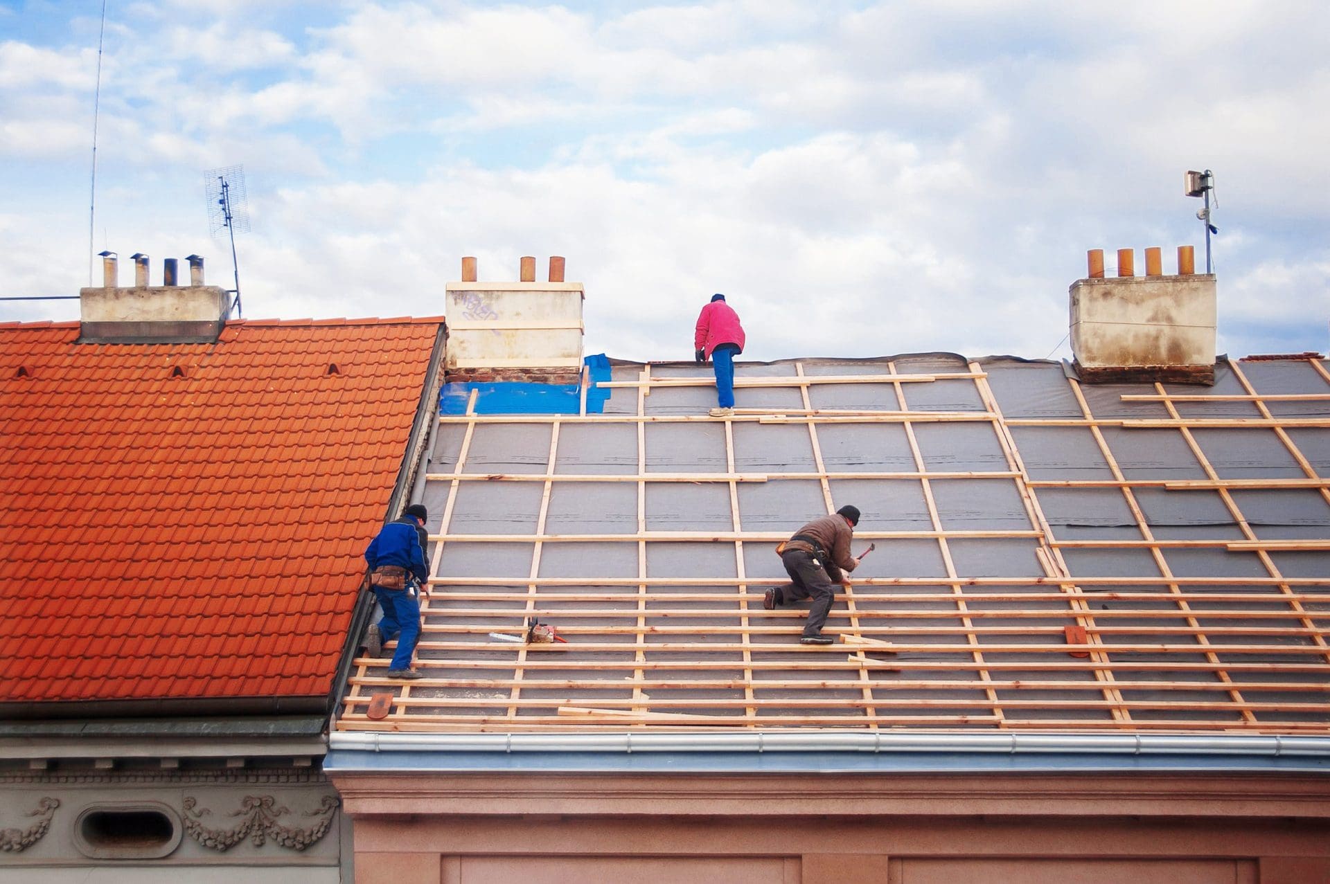 Three builders replace the tiled roof.