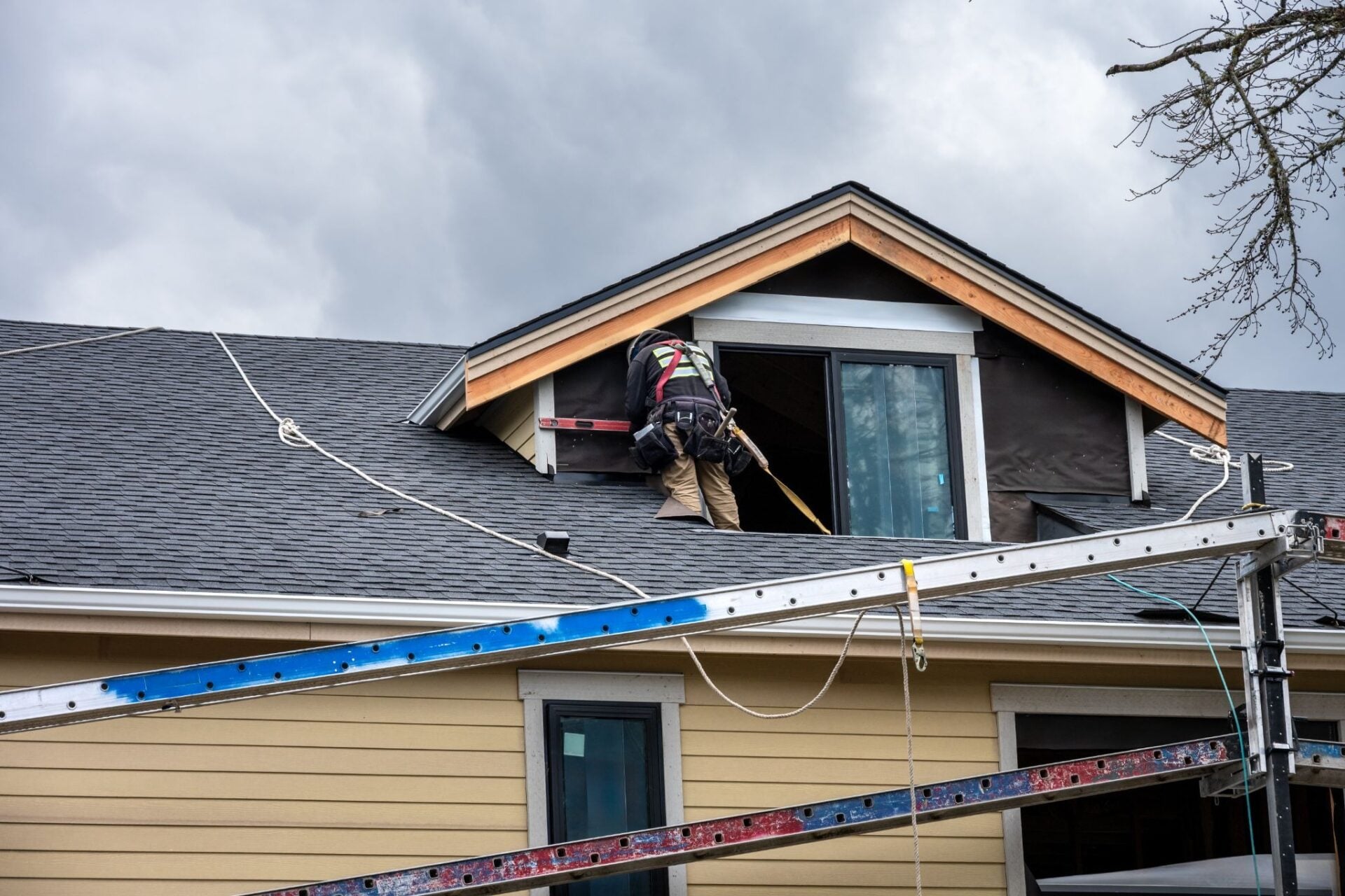 A person works on a roof near a dormer window.