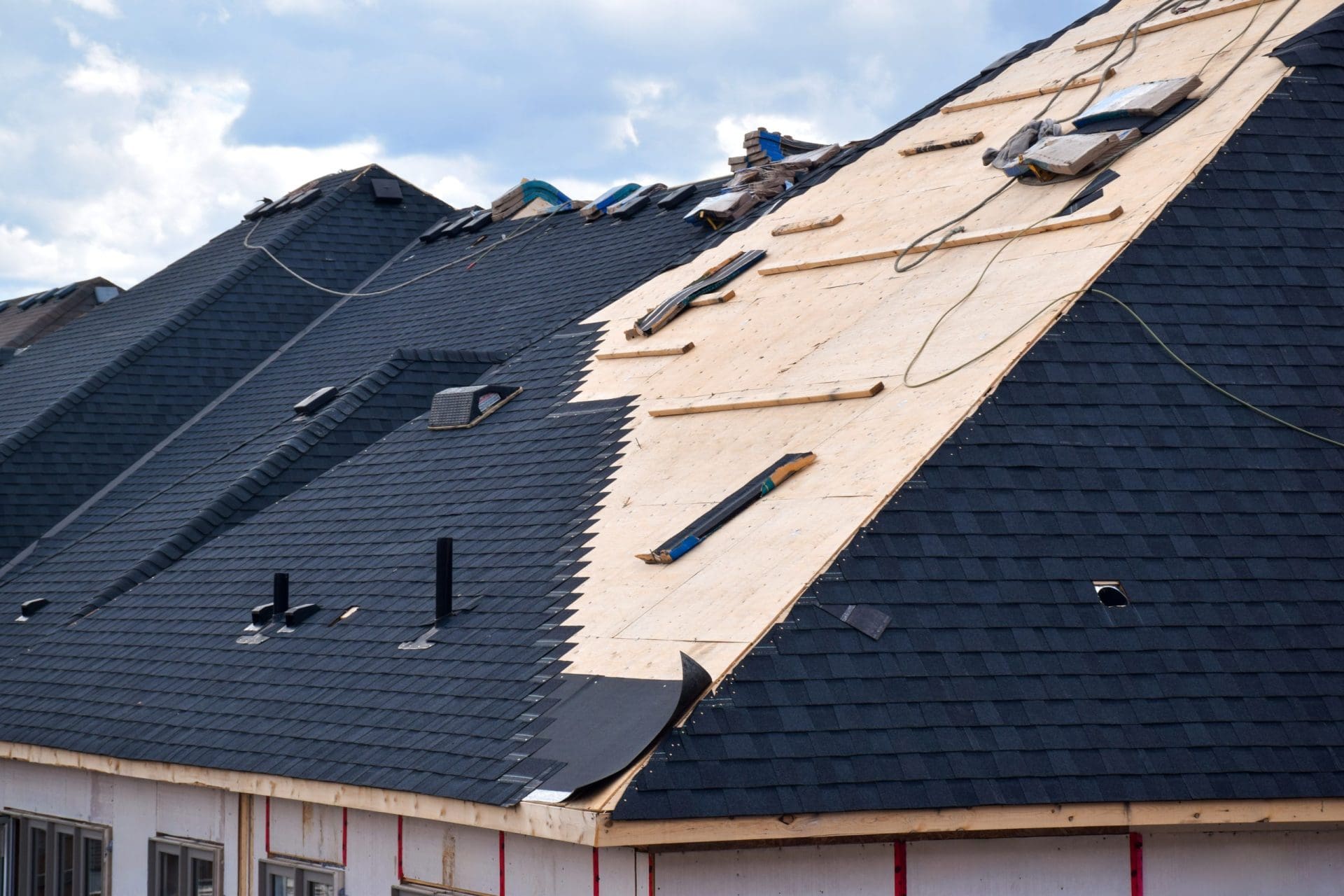 Closeup installation of black roof shingles on residential home.