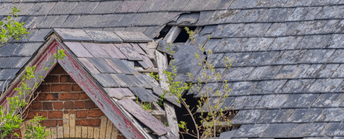 A roof with broken and missing shingles exposing the structure underneath.