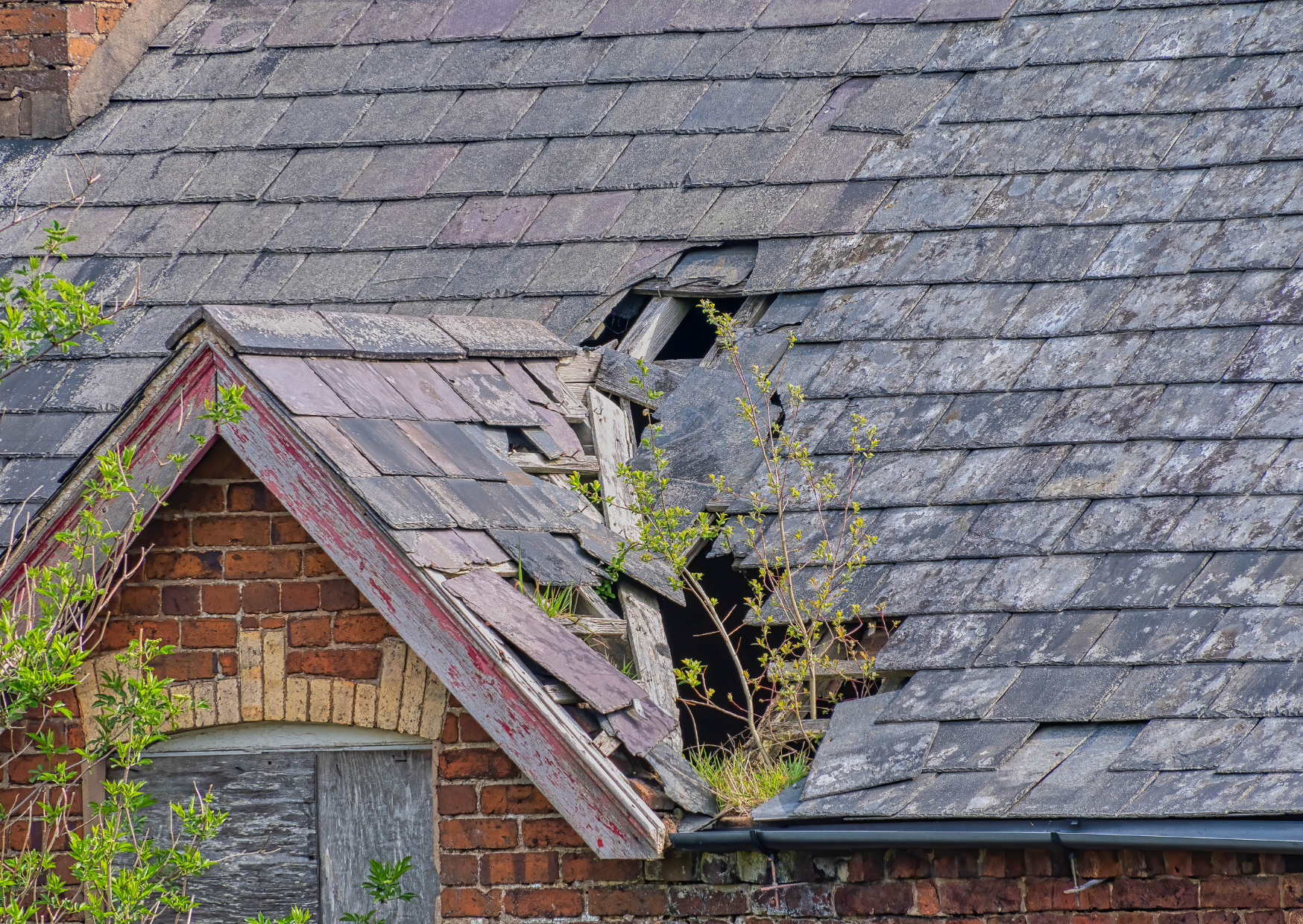A roof with broken and missing shingles exposing the structure underneath.