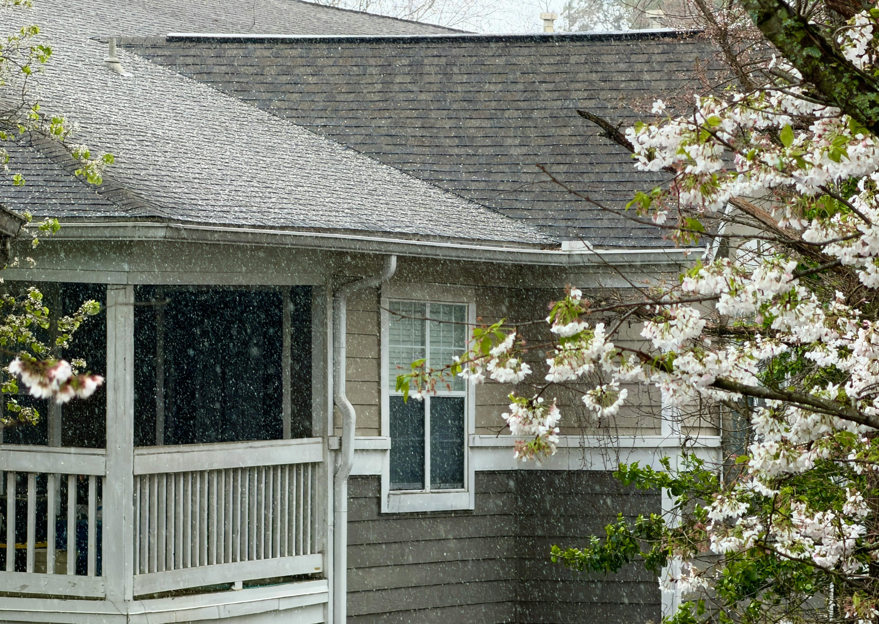 Residential house with visible rain falling around the roof and windows.