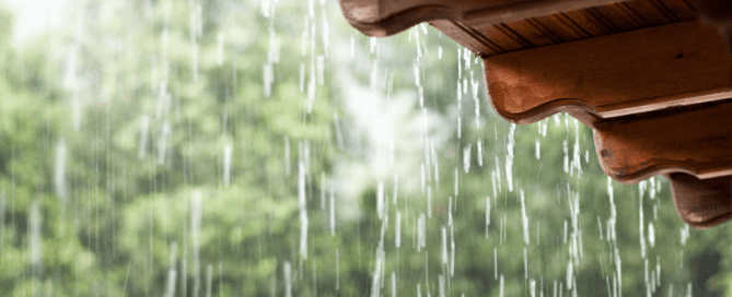 Water dripping from the edge of a roof during steady rainfall.