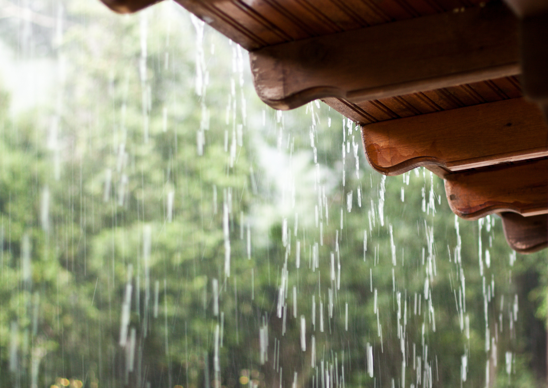 Water dripping from the edge of a roof during steady rainfall.