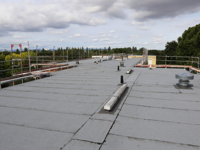 A large bitumen flat roof where the overlapping membrane sheets form visible seam lines running across the surface.